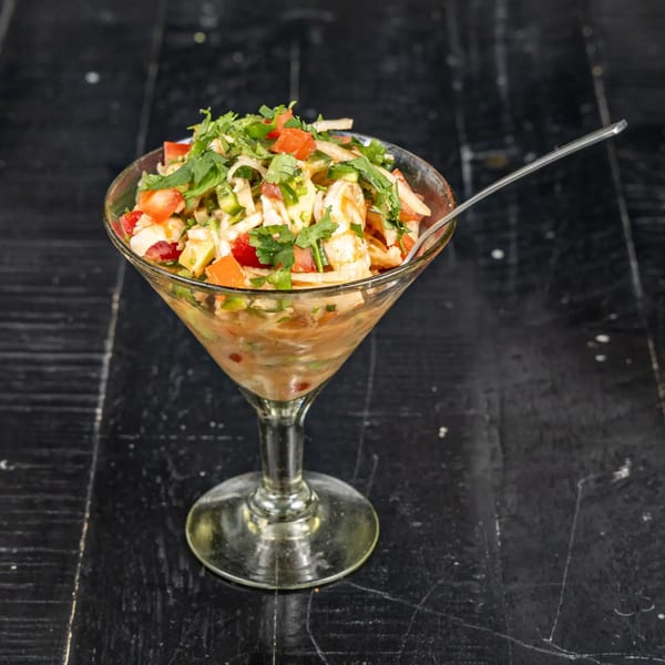 Neon Cactus Mexican ceviche in a martini glass with cilantro, tomatoes, and a spoon.