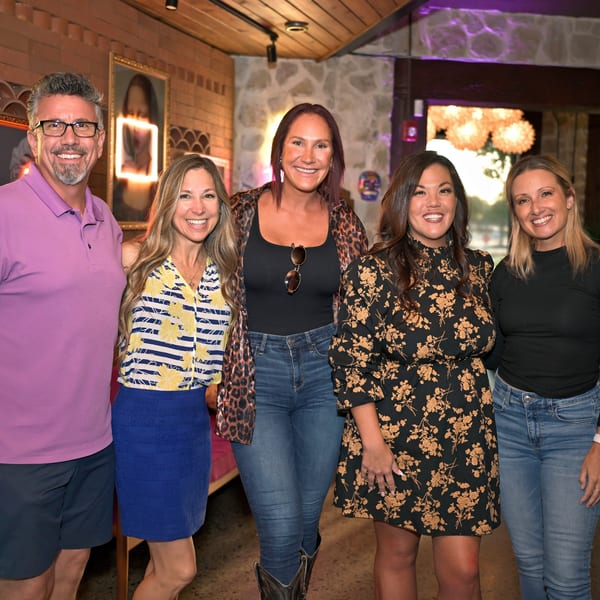 Five smiling people, three women and two men, posing together inside the Neon Cactus Mexican restaurant.