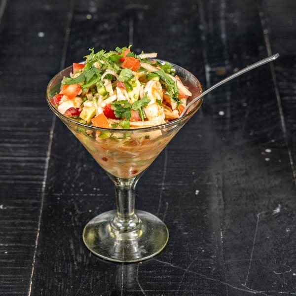 Neon Cactus Mexican ceviche in a martini glass with cilantro, tomatoes, and avocado.