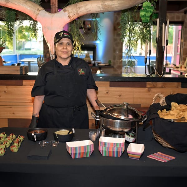 Neon Cactus chef stands proudly behind a buffet table with Mexican food and colorful serving dishes.