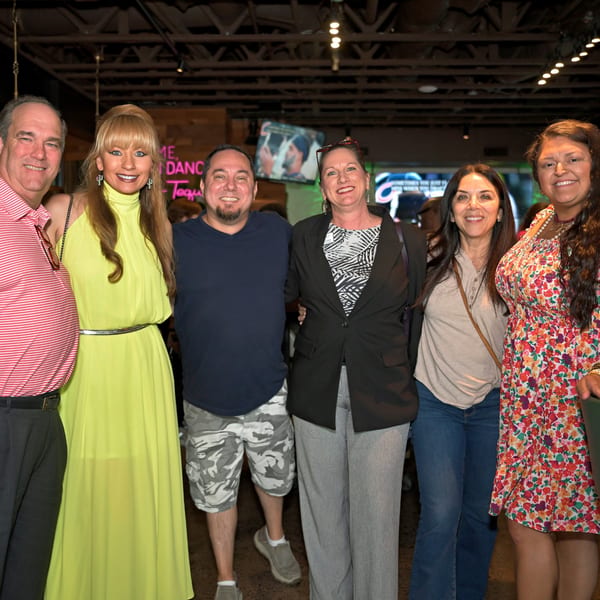 Six smiling people, three men and three women, posing together inside Neon Cactus restaurant.